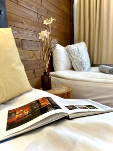 a book on a bed with a couch and a table at Red House Family house in Bansko