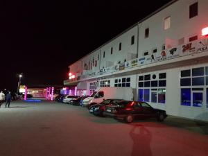 un edificio con coches estacionados en un estacionamiento por la noche en TALIJA, en Mrčajevci