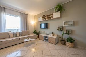 a living room with a couch and a tv at Nesto Athens Airport Den in Spáta