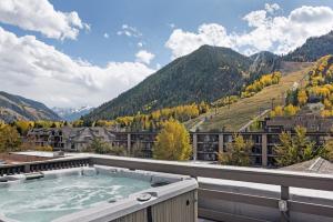 a hot tub on the roof of a building with mountains at Independence Square 210, Beautiful Studio with Kitchenette, Great Location in Downtown Aspen in Aspen