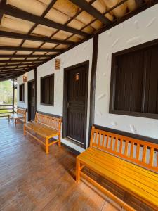 two benches sitting on the porch of a building at Pousada Entre Folhas in Serra do Cipo