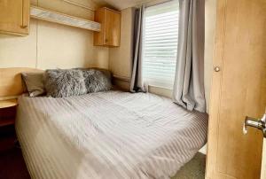 a small bed in a small room with a window at 8 berth pet friendly caravan, Penrhyn Bay, Llandudno in Llandudno