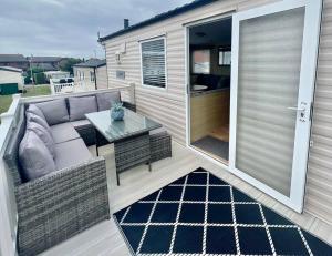 a patio with a couch and a table on a deck at 8 berth pet friendly caravan, Penrhyn Bay, Llandudno in Llandudno