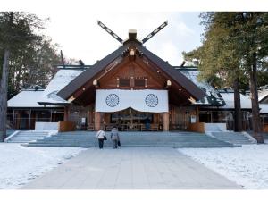 deux personnes debout devant un grand bâtiment dans l'établissement Hotel Tetora Spirit Sapporo - Vacation STAY 59361v, à Sapporo