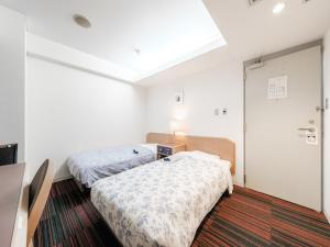two beds in a room with white walls at Hotel Tetora Spirit Sapporo - Vacation STAY 59346v in Sapporo