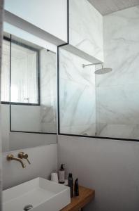 a white bathroom with a sink and a shower at Mare e Pietra -Pietra Luxury Villa Pefkali in Pefkali