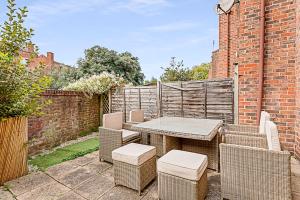 eine Terrasse mit einem Tisch, Stühlen und einer Ziegelwand in der Unterkunft Beautiful Richmond House in Richmond upon Thames