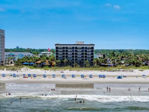 a beach with umbrellas and people in the water at Hampton Inn Oceanfront Jacksonville Beach in Jacksonville Beach