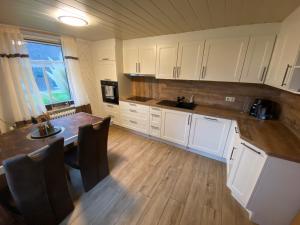 a kitchen with white cabinets and a wooden floor at Lüttje Huus Wirdum in Wirdum