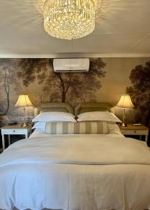 a bedroom with a large white bed with a chandelier at Môregroet in Kuruman