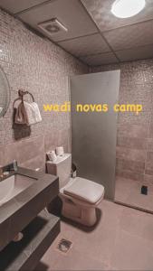 a bathroom with a toilet and a wash moves camp sign at wadi novas camp in Wadi Rum