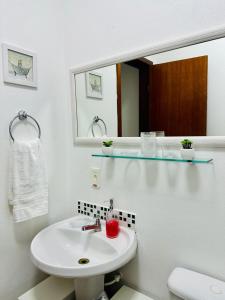 ein weißes Badezimmer mit einem Waschbecken und einem Spiegel in der Unterkunft Pousada Mar de Cristal in Florianópolis