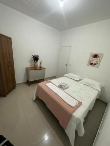 una camera bianca con letto e armadietto in legno di Hospedagem Espaço Rose Souza - Centro Histórico de Petrópolis - Aluguel de quartos a Petrópolis