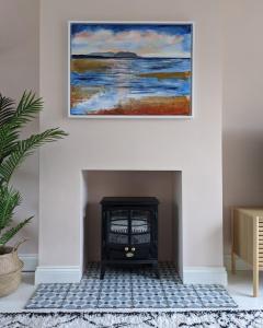 a fireplace with a painting hanging on a wall at Beautifully decorated large family home in seaside town with large garden in Colwyn Bay