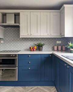 a blue kitchen with white cabinets and a sink at Beautifully decorated large family home in seaside town with large garden in Colwyn Bay
