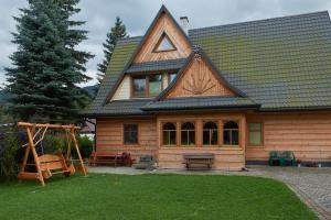 ein Holzhaus mit einer Schaukel und einem Spielplatz in der Unterkunft Country Home in heart of Tatra mountains in Zakopane