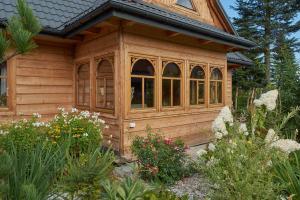 ein kleines Holzhaus in einem Garten mit Blumen in der Unterkunft Country Home in heart of Tatra mountains in Zakopane