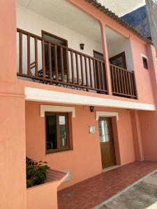 ein rosafarbenes Haus mit einem Balkon und einer Treppe in der Unterkunft Os netos de Fina e Tino in Cariño