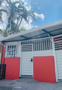 un garaje con puertas rojas y blancas y palmeras en Apartamento-San José-WiFi, en San José