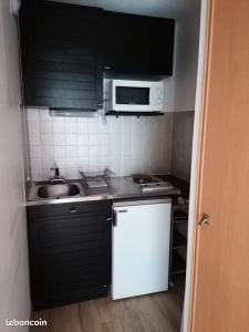 a small kitchen with a sink and a microwave at Studio Cauterets centre - le Macadau in Cauterets