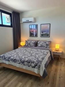 a bedroom with a bed and two lamps and two windows at Appartement F2 Ninirei in Papeete