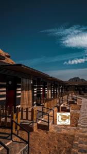 un groupe de bancs en bois devant un bâtiment dans l'établissement Victoria Desert Camp, à Disah