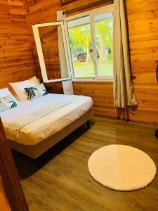 1 dormitorio con cama, ventana y alfombra en Bungalow TEIPO en Teavaro