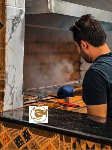 Un homme cuisine de la nourriture sur un grill dans l'établissement Victoria Desert Camp, à Disah