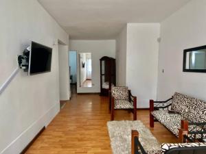 sala de estar con 2 sillas y TV en la pared en Casa Laura, en Medellín