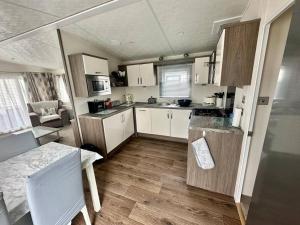 una pequeña cocina con armarios blancos y una mesa en 6 berth luxury caravan, Lyons Winkups Holiday Park, en Kinmel Bay