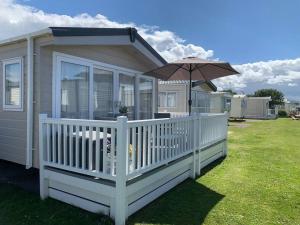 una pequeña casa con un paraguas en un patio en 6 berth luxury caravan, Lyons Winkups Holiday Park, en Kinmel Bay