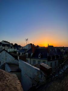 una puesta de sol sobre una ciudad con casas y edificios en La tanière du sorcier en Saumur
