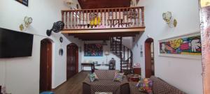 a living room with a staircase and a couch at Casa Rosa de Peruíbe - Casa de Temporada 3 dormitórios, 10 hóspedes, piscina, wi-fi, netflix, 800 metros da praia in Peruíbe