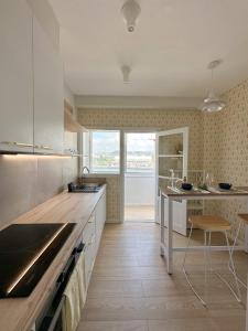 a kitchen with white cabinets and a counter with a table at Airiños da ría in Pontevedra