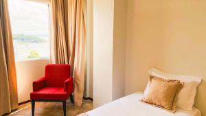 a bedroom with a red chair and a bed and a window at Hotel Atlantico Macaé By Inn House in Macaé