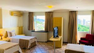 a hotel room with two beds and a flat screen tv at Hotel Atlantico Macaé By Inn House in Macaé