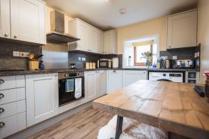 a kitchen with white cabinets and a wooden table at Croft House, Armadale Bay in Armadale