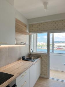 a kitchen with white cabinets and a large window at Airiños da ría in Pontevedra