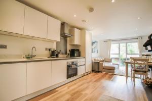 a kitchen with white cabinets and a dining room at Luxurious 1 Bedroom West Bridgford Apartment in Nottingham