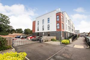 a white building with a fence in a parking lot at Luxurious 1 Bedroom West Bridgford Apartment in Nottingham