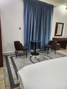 a room with two chairs and a table and a blue curtain at طرف الطريق in Al Ḩawīyah