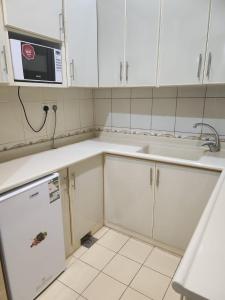 a kitchen with white cabinets and a sink and a microwave at طرف الطريق in Al Ḩawīyah