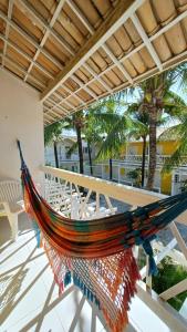 a hammock on a patio with palm trees at Pousada Barra Bonita in Barra de São Miguel