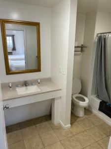 a bathroom with a sink and a toilet and a mirror at Lake View Inn Lake George in Lake George