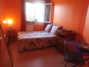 een slaapkamer met oranje muren en een bed en een raam bij Logerthine Bezons in Bezons