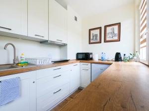 cocina con armarios blancos y suelo de madera en Apartament Sandomierski, en Sandomierz