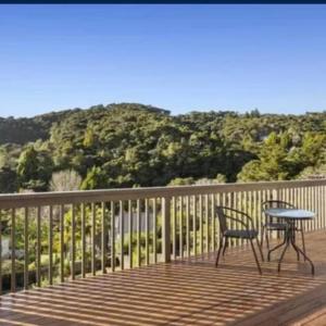 a table and a chair on a deck with a mountain at Paihia Retreat in Paihia