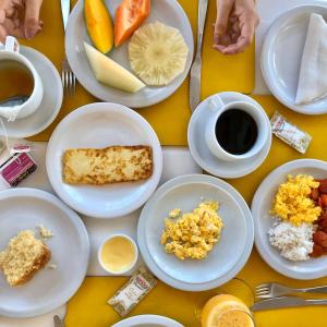 a table with plates of food and a cup of coffee at Pousada Barra Bonita in Barra de São Miguel