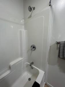 La salle de bains blanche est pourvue d'un lavabo et d'une douche. dans l'établissement Lake View Inn Lake George, à Lake George