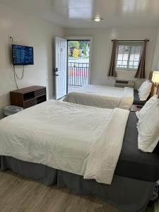 a bedroom with two beds and a television and a window at Lake View Inn Lake George in Lake George